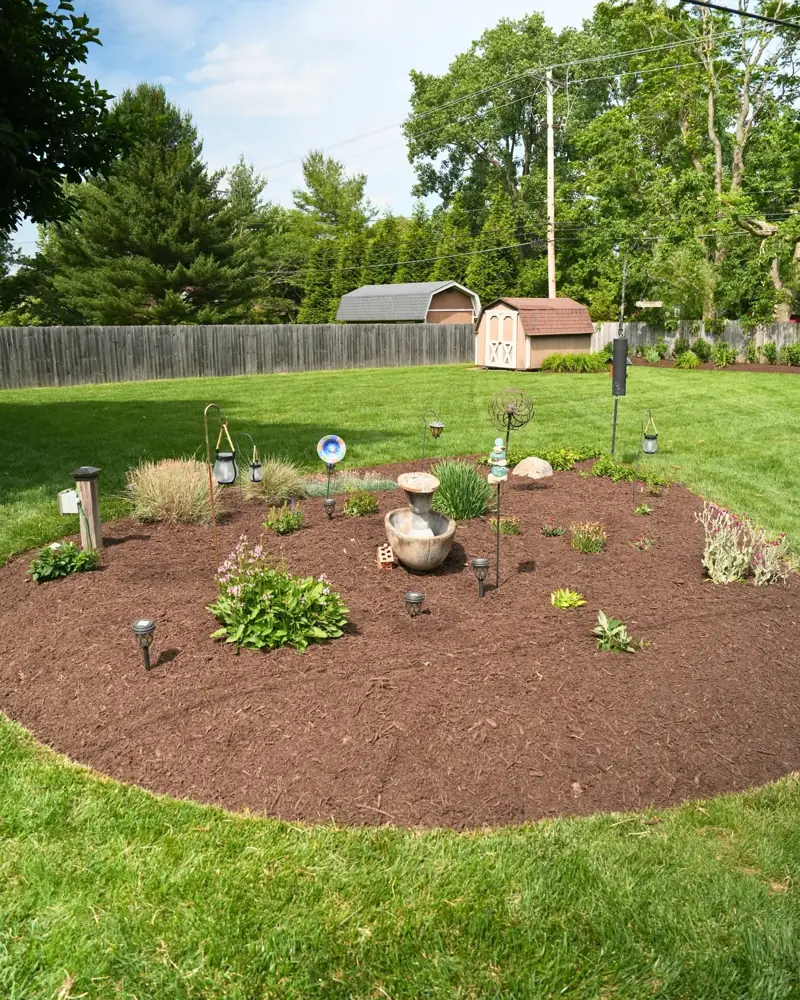 Large mulch bed with fountain and plantings in a Dayton, OH backyard